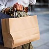 Person carrying a kraft paper shopping bag