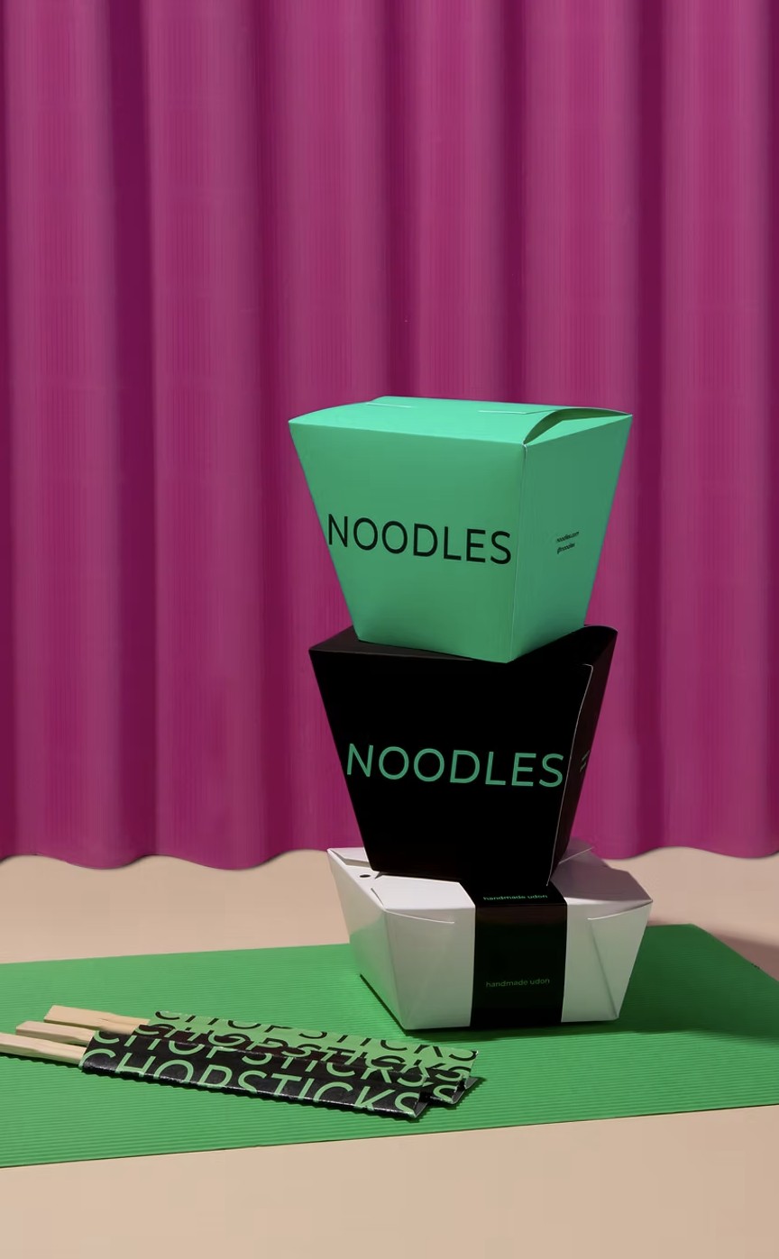 Stacked branded takeout noodle boxes with custom chopstick packaging